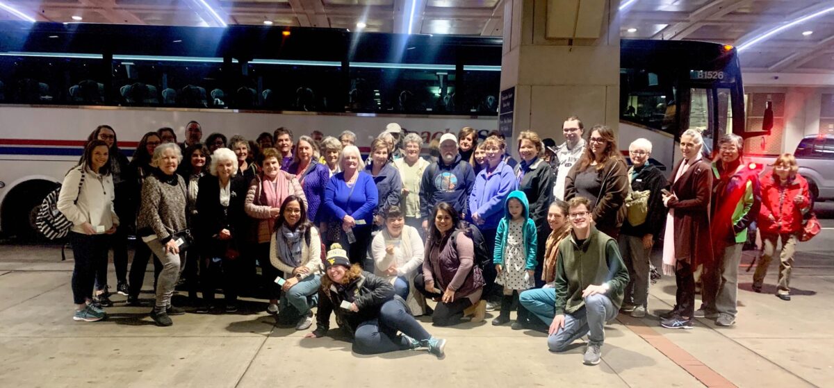 Bus trip attendees smiling together in front of the bus, excited for the Philadelphia Flower Show